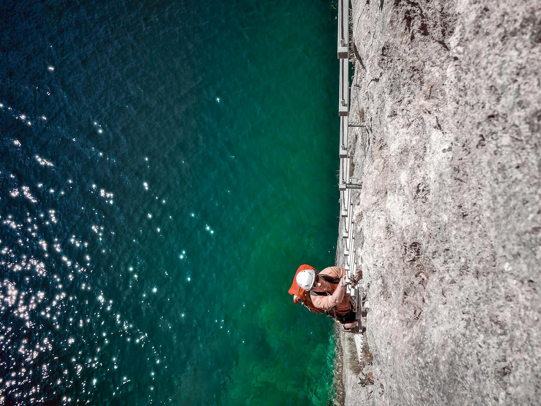 Climber ascending rock face with safety equipment