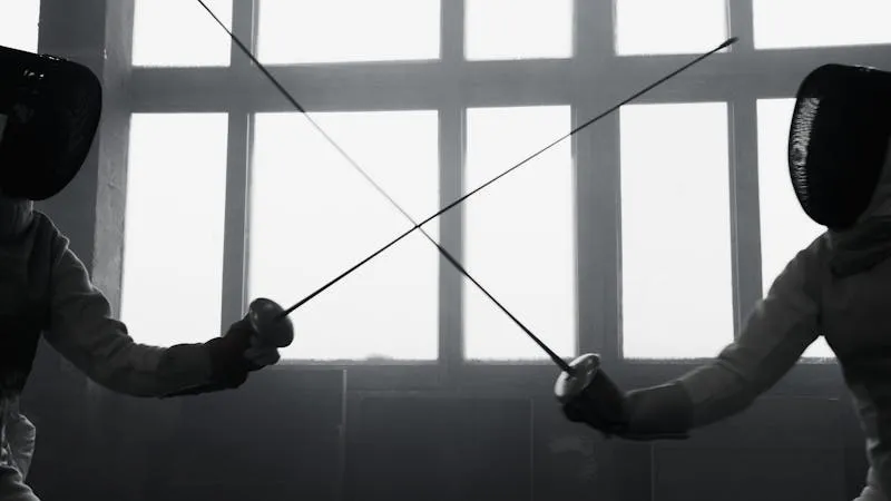 Two fencers dueling with swords in competition
